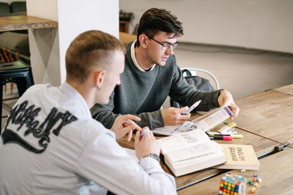 Two people sat at a desk reading English grammar books